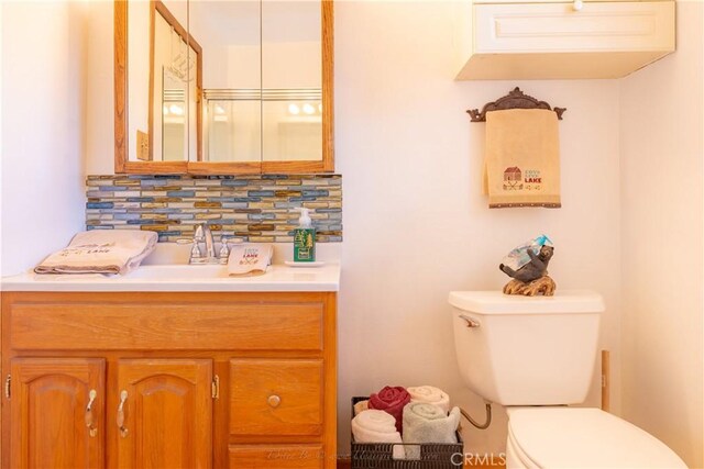 half bath with vanity, toilet, and tasteful backsplash