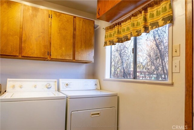 clothes washing area featuring cabinet space and separate washer and dryer