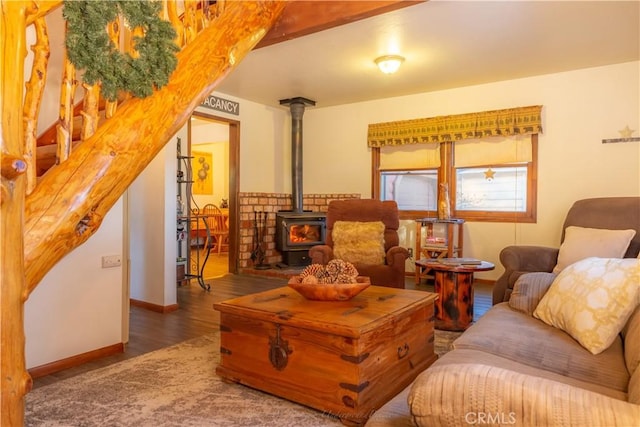 living area featuring baseboards, wood finished floors, and a wood stove