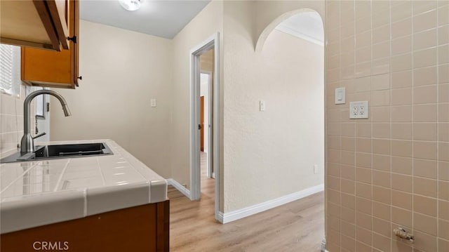 kitchen featuring tile countertops, sink, and light hardwood / wood-style flooring