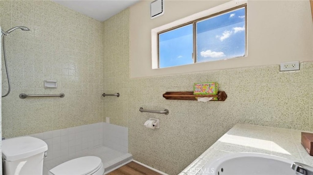 bathroom with tiled shower, toilet, and tile walls