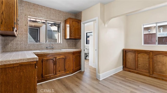 kitchen featuring backsplash, light wood-type flooring, and sink