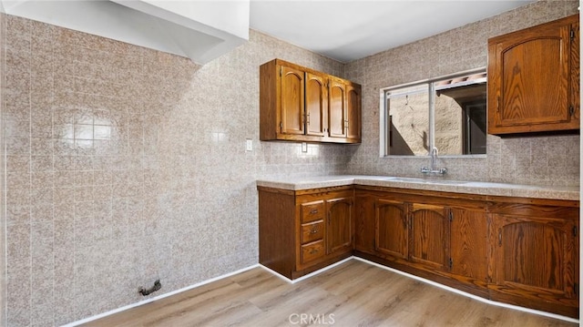 kitchen featuring sink, tile walls, and light wood-type flooring