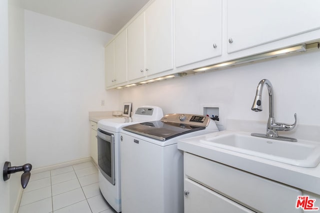 clothes washing area featuring washing machine and clothes dryer, sink, light tile patterned floors, and cabinets