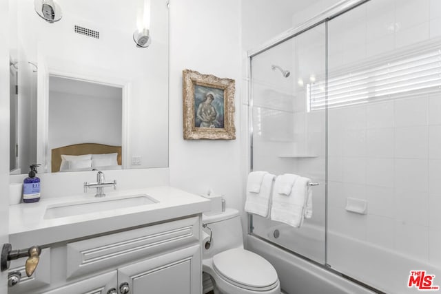 full bathroom featuring toilet, combined bath / shower with glass door, and vanity