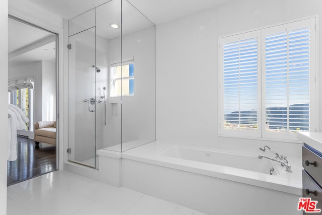 bathroom featuring tile patterned flooring, vanity, a healthy amount of sunlight, and plus walk in shower