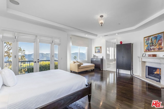 bedroom featuring a mountain view, dark wood-type flooring, french doors, a raised ceiling, and access to exterior