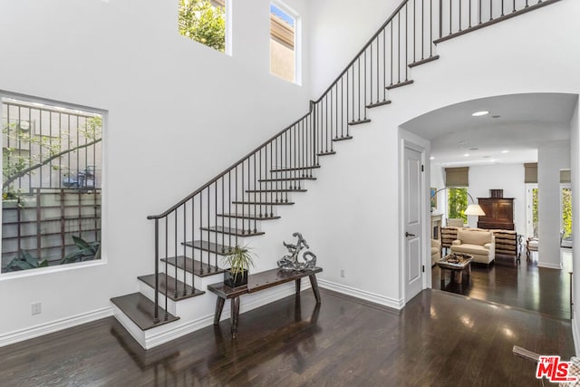 staircase with a towering ceiling and hardwood / wood-style flooring