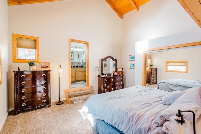 carpeted bedroom with ensuite bath, wooden ceiling, beamed ceiling, and high vaulted ceiling