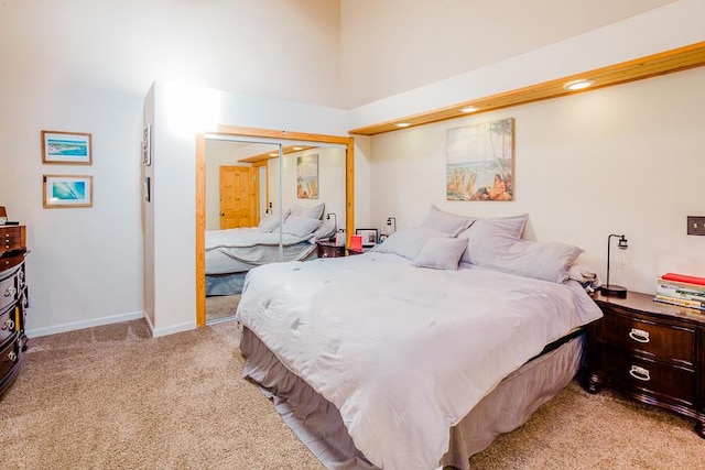 bedroom featuring light colored carpet, a closet, and a towering ceiling