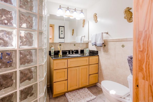 bathroom with tile walls, toilet, and vanity