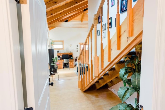 staircase featuring beam ceiling, wood-type flooring, wood ceiling, and high vaulted ceiling