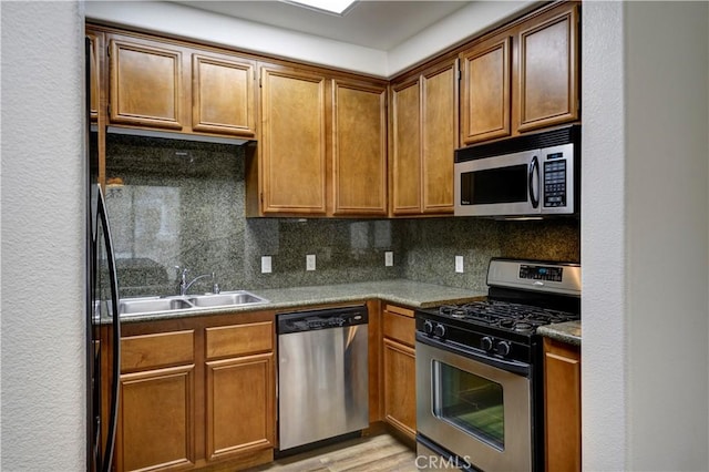 kitchen featuring decorative backsplash, sink, appliances with stainless steel finishes, and light hardwood / wood-style flooring