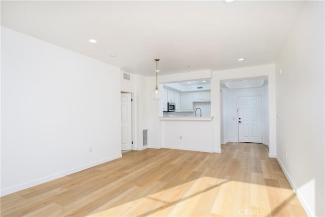 unfurnished living room with light hardwood / wood-style flooring and sink