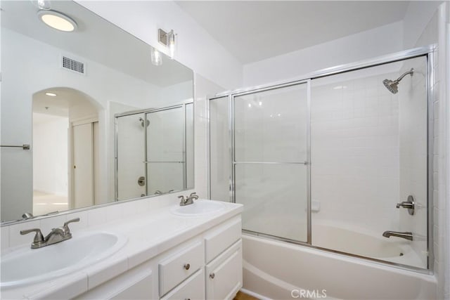 bathroom featuring combined bath / shower with glass door and vanity