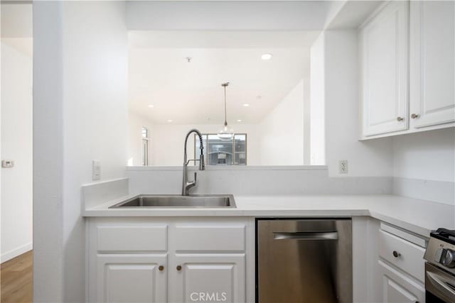 kitchen with white cabinetry, kitchen peninsula, appliances with stainless steel finishes, hanging light fixtures, and sink