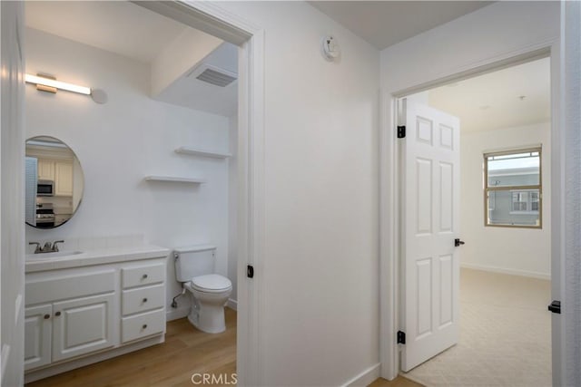 bathroom featuring toilet, wood-type flooring, and vanity