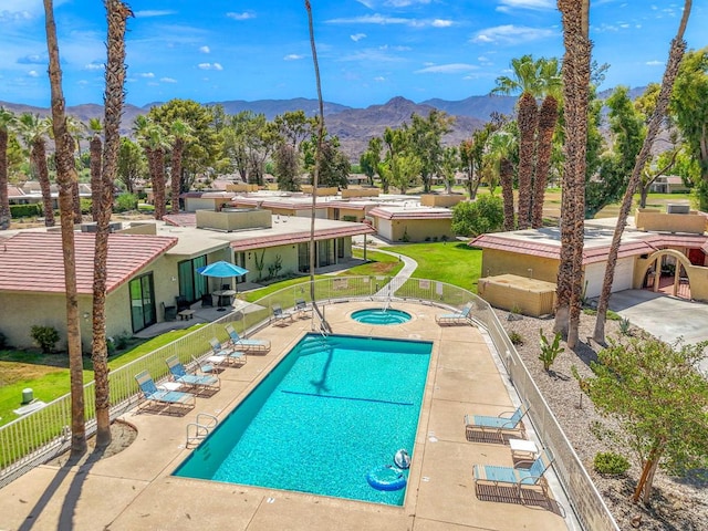 view of swimming pool with a community hot tub, a mountain view, and a patio area