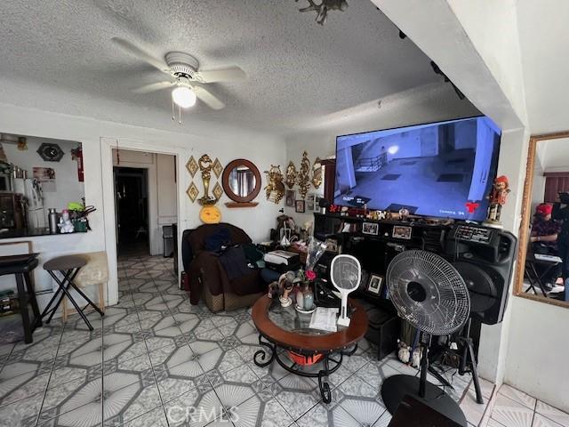 living area featuring ceiling fan and a textured ceiling