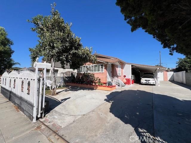 view of front facade featuring fence, a carport, and concrete driveway