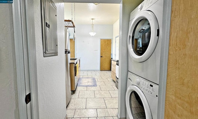 laundry room featuring stacked washer / dryer and light tile patterned flooring