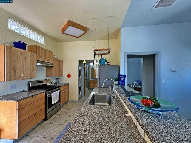 kitchen with stacked washer / drying machine, appliances with stainless steel finishes, and sink