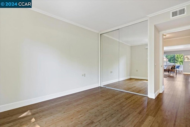 empty room featuring ornamental molding and dark wood-type flooring