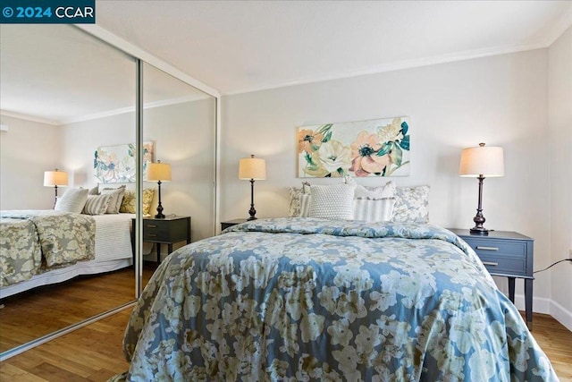 bedroom featuring a closet, dark wood-type flooring, and crown molding