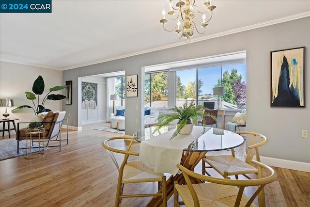 dining area featuring a notable chandelier, ornamental molding, and light hardwood / wood-style flooring