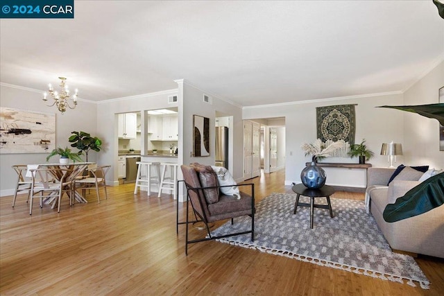 living room with ornamental molding, light hardwood / wood-style flooring, and an inviting chandelier