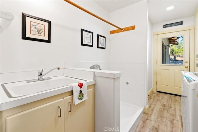 clothes washing area with sink and light hardwood / wood-style flooring