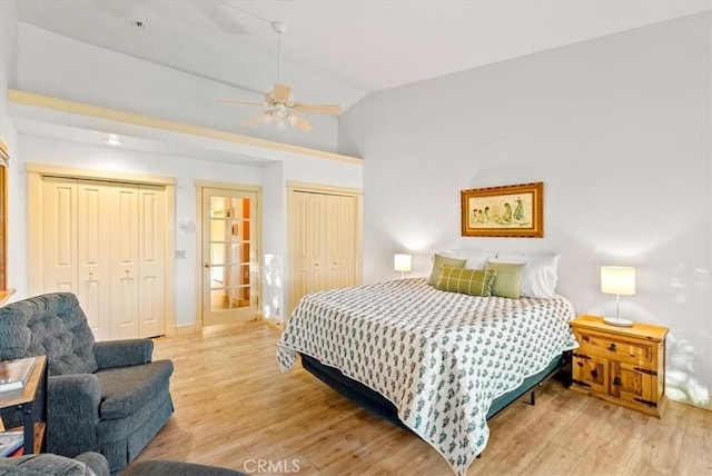 bedroom with ceiling fan, light wood-type flooring, lofted ceiling, and two closets