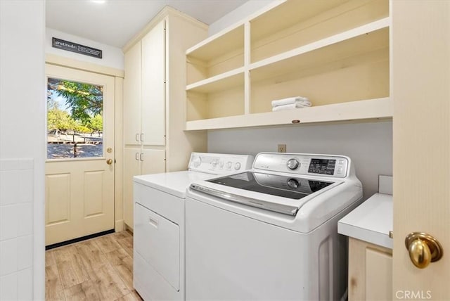 washroom featuring light hardwood / wood-style floors, cabinets, and washing machine and clothes dryer