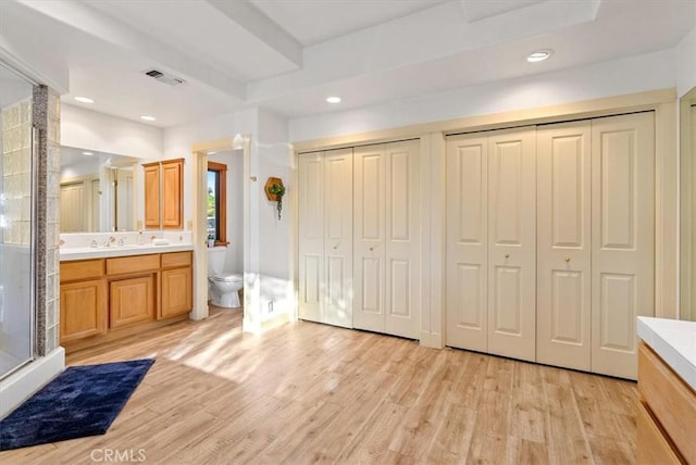 bathroom featuring toilet, vanity, an enclosed shower, and hardwood / wood-style flooring