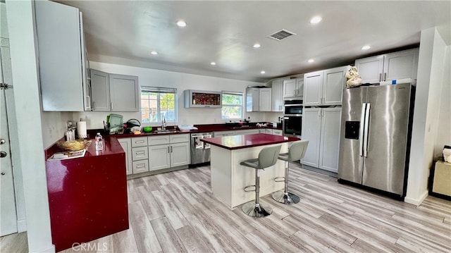 kitchen featuring sink, appliances with stainless steel finishes, light hardwood / wood-style floors, and a center island