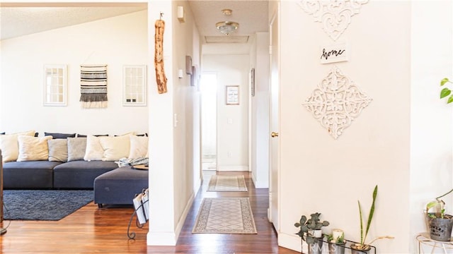 hall with lofted ceiling, baseboards, and wood finished floors