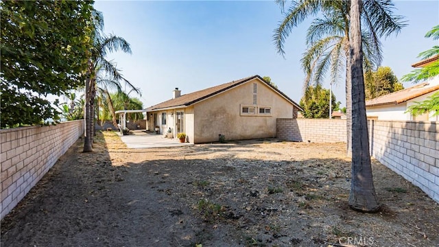 rear view of property with a fenced backyard, a patio, and stucco siding