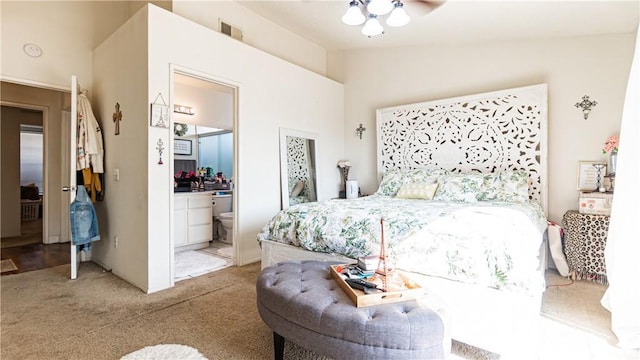 bedroom featuring light colored carpet, visible vents, connected bathroom, vaulted ceiling, and ceiling fan