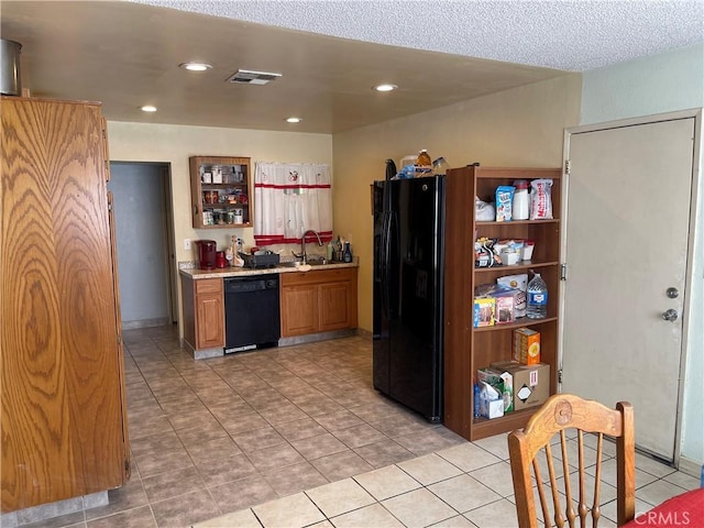 kitchen with sink, light tile patterned flooring, black appliances, and a textured ceiling