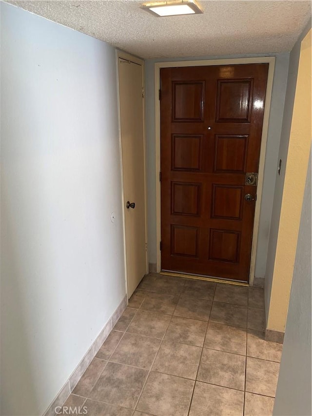 hallway featuring light tile patterned flooring and a textured ceiling