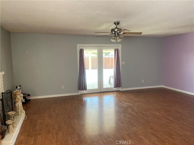 unfurnished living room featuring a brick fireplace, dark hardwood / wood-style floors, a textured ceiling, and french doors