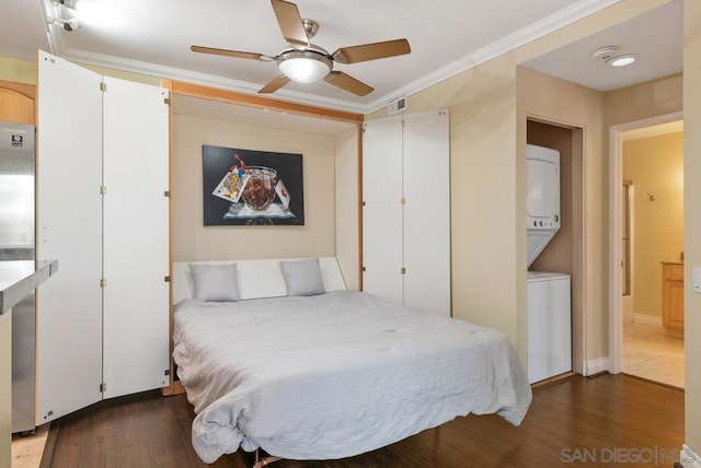 bedroom featuring stacked washer / drying machine, crown molding, dark hardwood / wood-style flooring, and ceiling fan