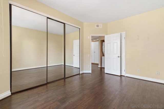 unfurnished bedroom with a closet and dark hardwood / wood-style floors