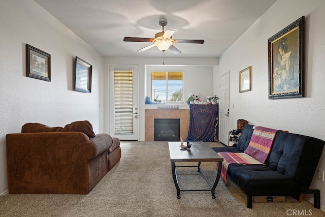 living room with a tile fireplace, carpet flooring, and ceiling fan