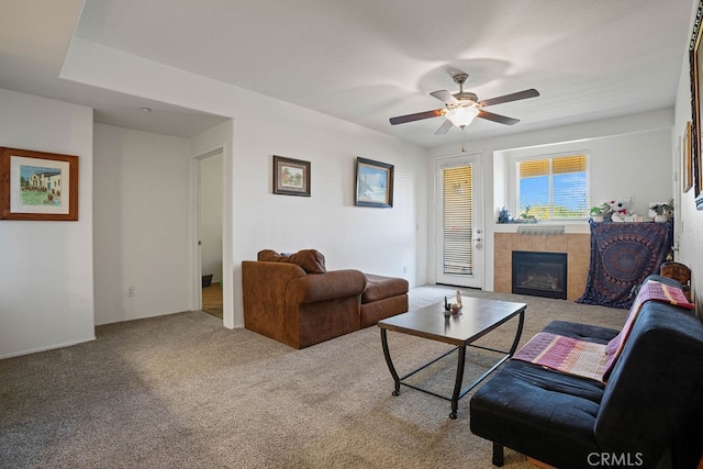 living room featuring carpet flooring, a fireplace, and ceiling fan