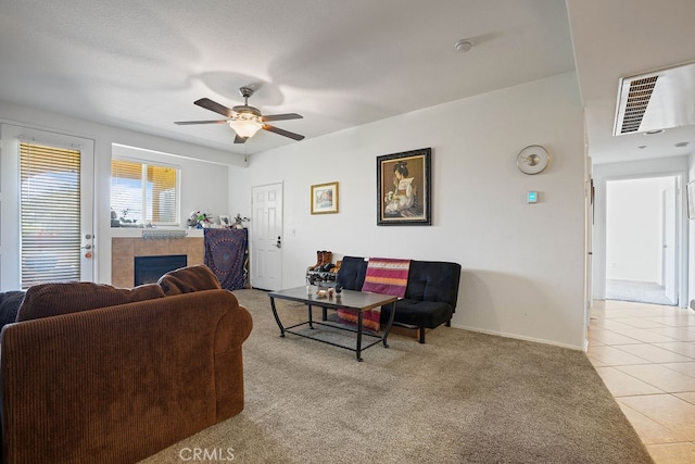 tiled living room with ceiling fan and a tile fireplace