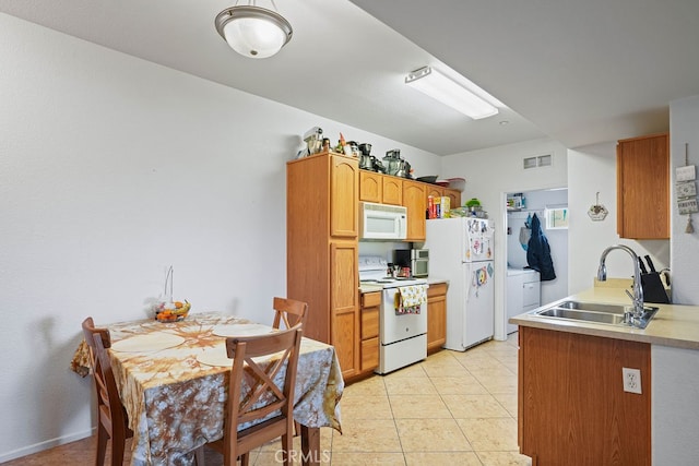 kitchen featuring white appliances, light tile patterned floors, washer / clothes dryer, and sink