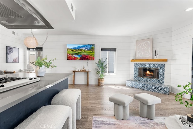 living room featuring wood-type flooring, a fireplace, and wooden walls