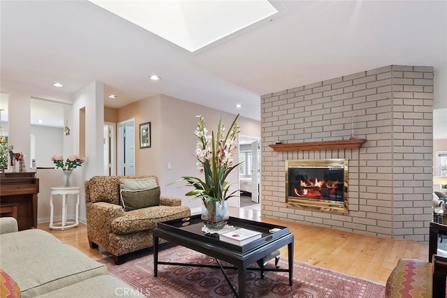 living room featuring a fireplace, a skylight, and hardwood / wood-style flooring