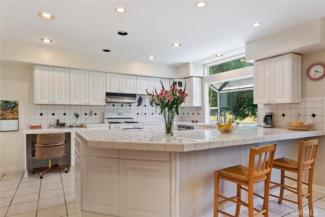 kitchen with backsplash, white cabinetry, white range with gas cooktop, and tile countertops